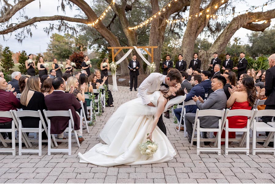 Groom kissing the bride at the end of the aisle after wedding
