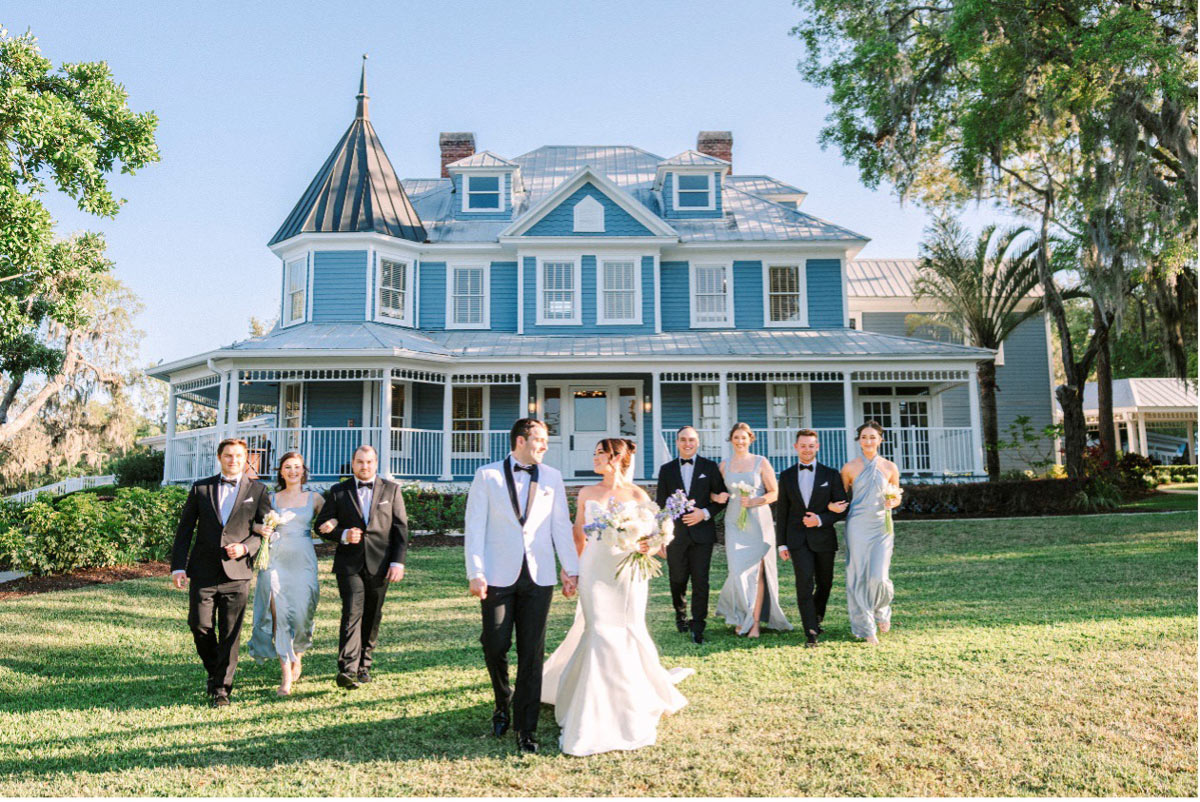 01-bride and groom walking on the lawn with the bridal party in front of the Highland Manor in Apopka