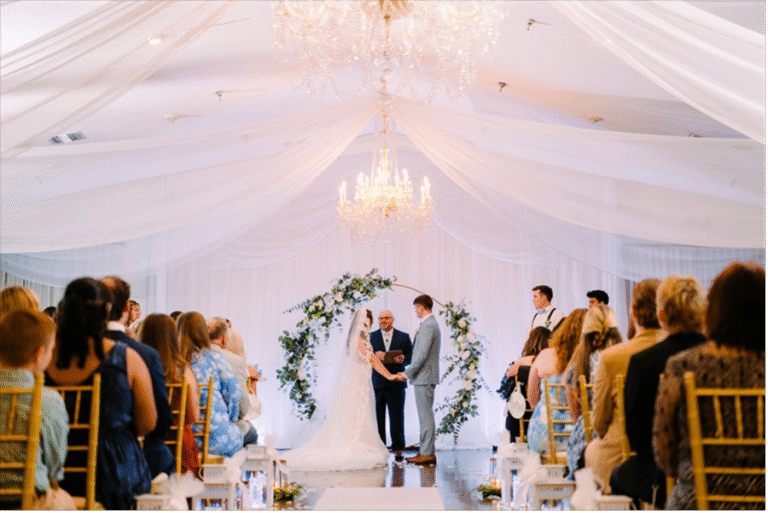 indoor wedding ceremony under chandalier and draped shear fabric
