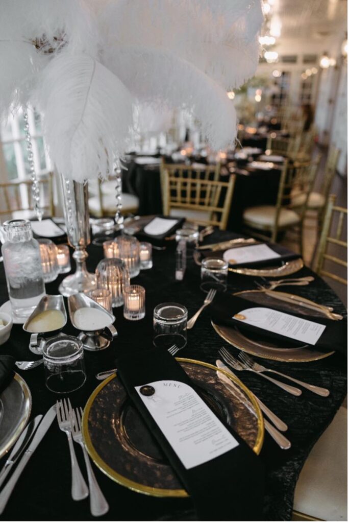 wedding reception table display with black table cloths and plates with gold trim for an elegant feel