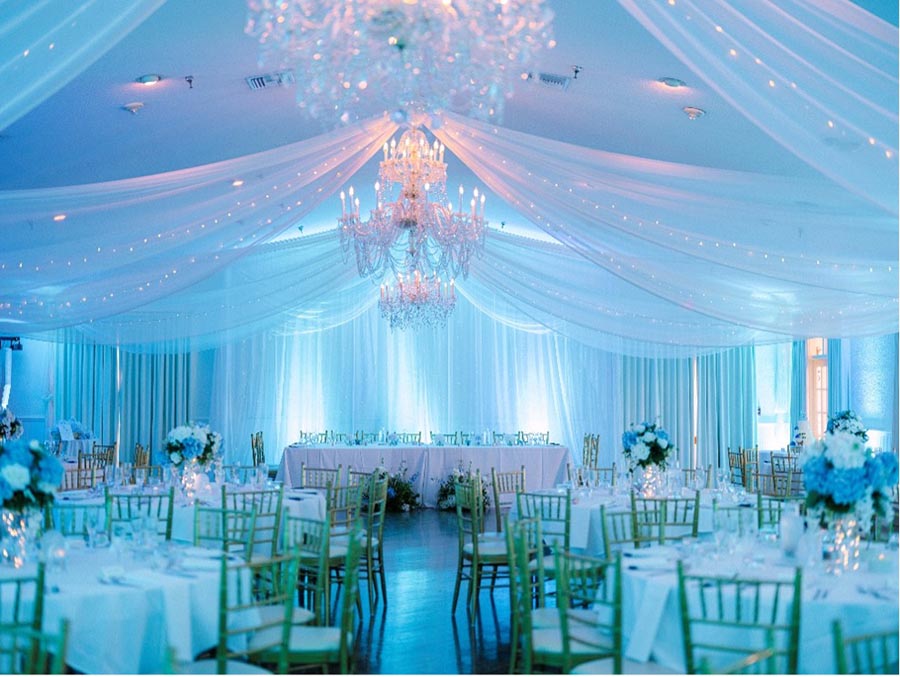 wedding reception hall with chandeliers and shear fabric draped from ceiling