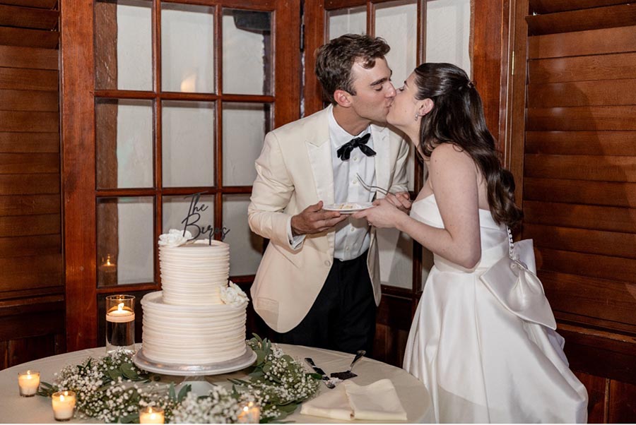 bride and groom kissing by their wedding cake