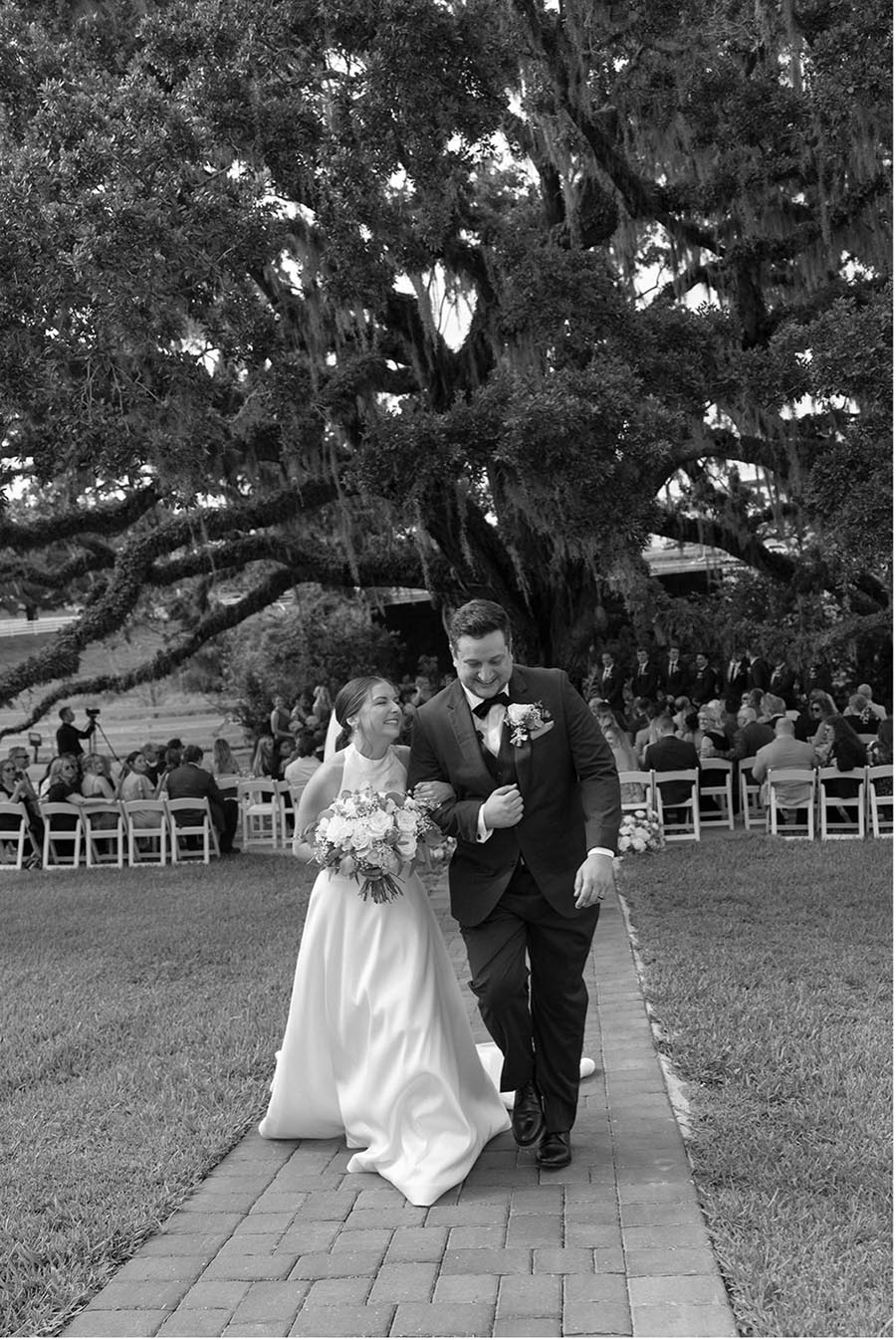 - 12 bride and groom walking down the aisle after their outdoor wedding with a large oak tree in the background