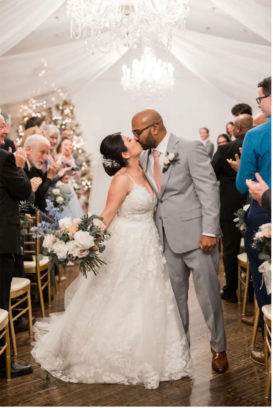 Bride and Groom kissing in the aisle under chandeliers