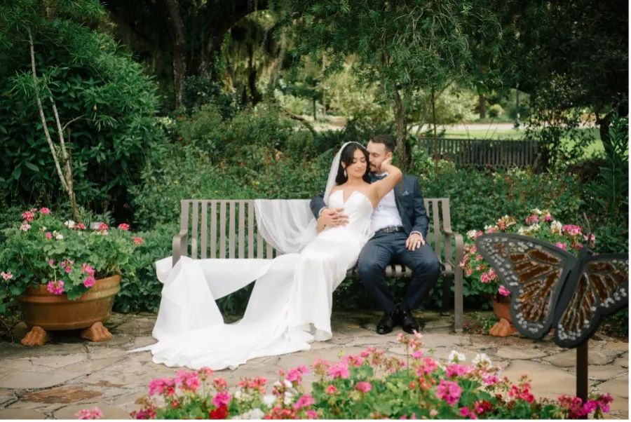 Bride and Groom sitting on a bench in the outdoor garden area