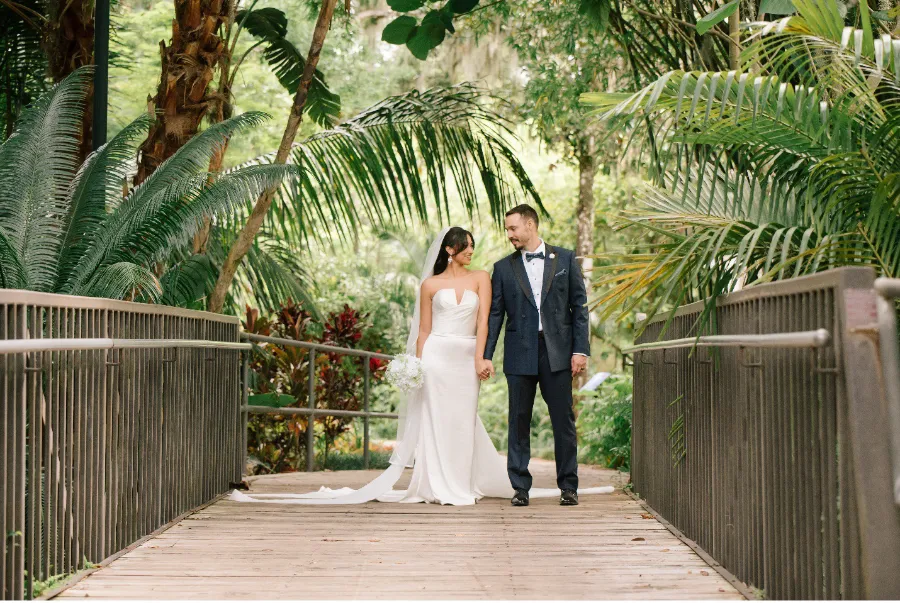 Bride and Groom walking along bridge in the outdoor gardens
