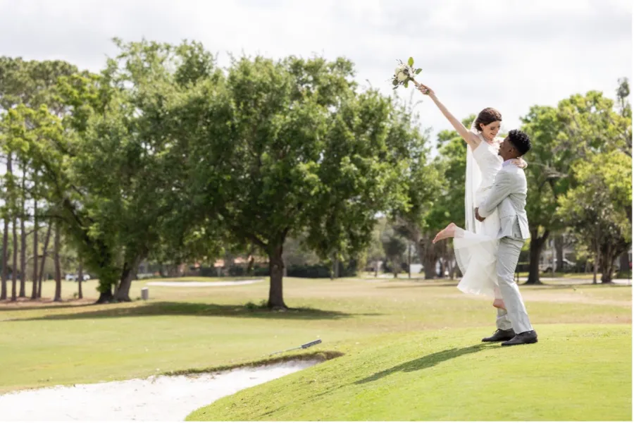Bride in the arms of her groom on the golf course