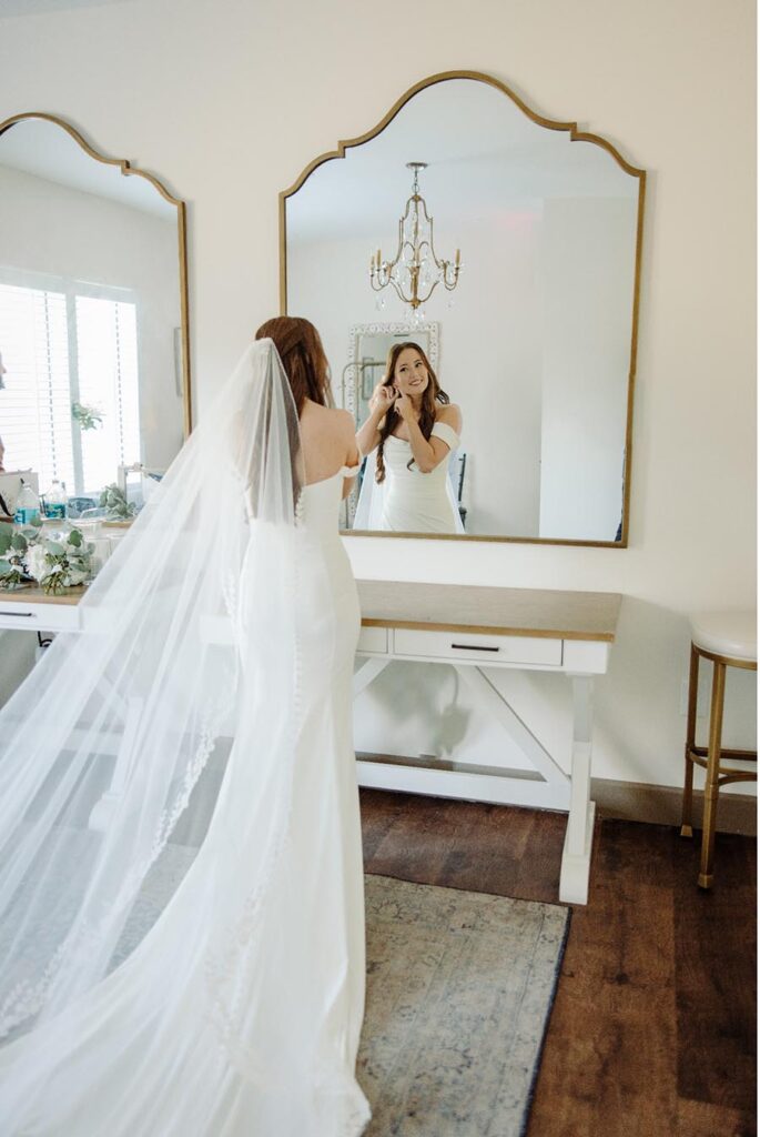 Bride puting on earings in front of mirror in Bridal Suite at Azalea Lodge Orlando