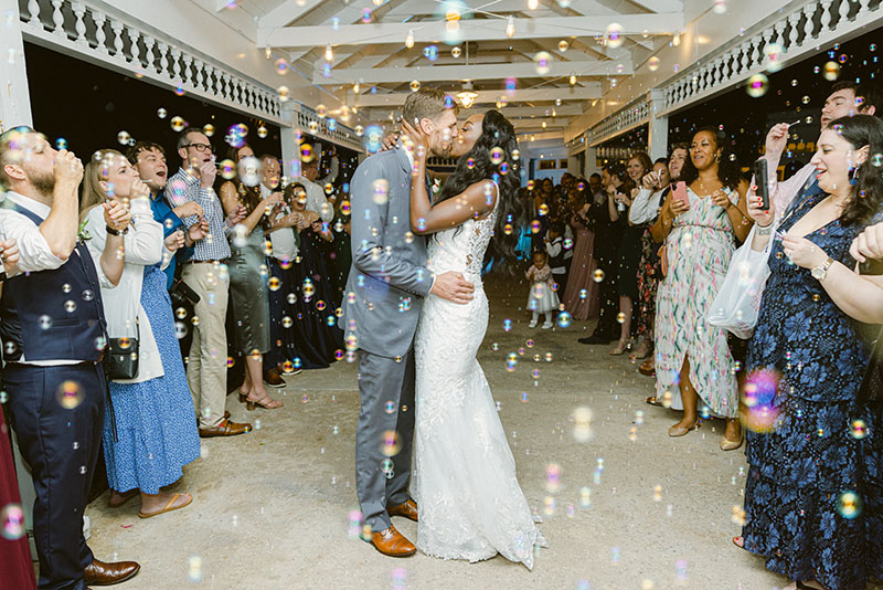 Wedding couple leaving the reception among guests blowing bubbles