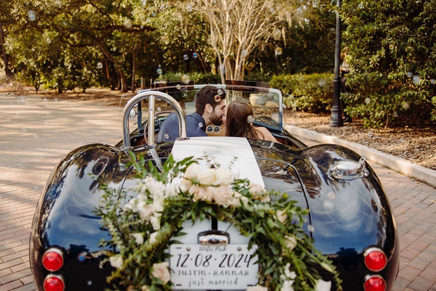 Just Married Couple kissing while sitting in an AC Cobra sports car