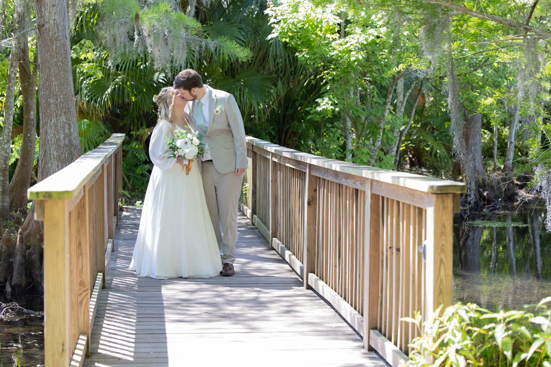 bride and groom walking across wooden bridge after their intimate garden wedding