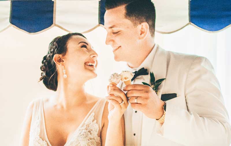 Bride and groom smiling at each other while holding ice cream cones.