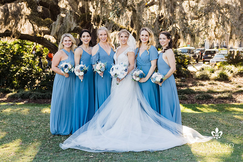 Wedding pro tip - bride and bridesmaids standing in front of large oak tree.